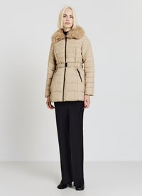 Manteau matelassé beige avec col en fausse fourrure, taille ceinturée et poches latérales zippées. Présente une texture matelassée et un col montant.