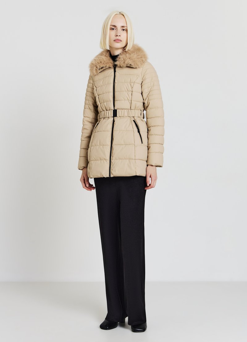 Manteau matelassé beige avec col en fausse fourrure, taille ceinturée et poches latérales zippées. Présente une texture matelassée et un col montant.