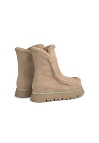Bottes en suède beige avec doublure en fourrure et texture douce. Présente un bord métallique décoratif et une semelle robuste et texturée.