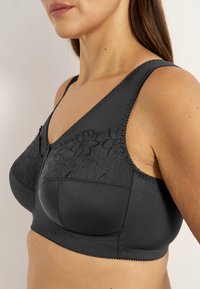 Svart bh med blommig broderi, breda band och slätt tyg. Designen inkluderar en mjuk textur med detaljerad sömnad.