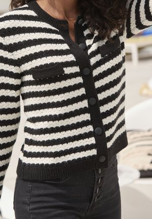 Sweter w czarno-białe paski o fakturze dzianiny, z zapinanym na guziki przodem, dwoma przednimi kieszeniami oraz ściągaczami na rękawach i u dołu.