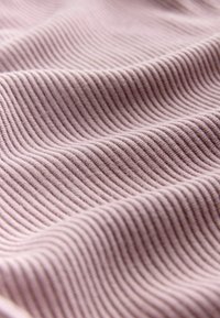 Mīksts, ribots audums maigā purpursarkanā krāsā ar gludu faktūru, uz virsmas redzamas pārmaiņus paceltas un gludas līnijas.