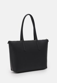 Černá taška typu tote s hladkou texturou, dvěma dlouhými uchy, obdélníkového tvaru a zapínáním na zip nahoře. Žádné viditelné kovové prvky nebo ozdoby.
