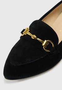 Μαύρα loafers από καστόρι με μυτερή μύτη και χρυσές μεταλλικές λεπτομέρειες στο μπροστινό μέρος. Διαθέτουν ραφές και λεία φόδρα εσωτερικά.