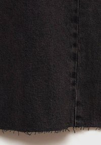 Črn denimski material z razfrkanim robom, vertikalnimi šivi in teksturirano površino. Material ima nekoliko zbledel videz.