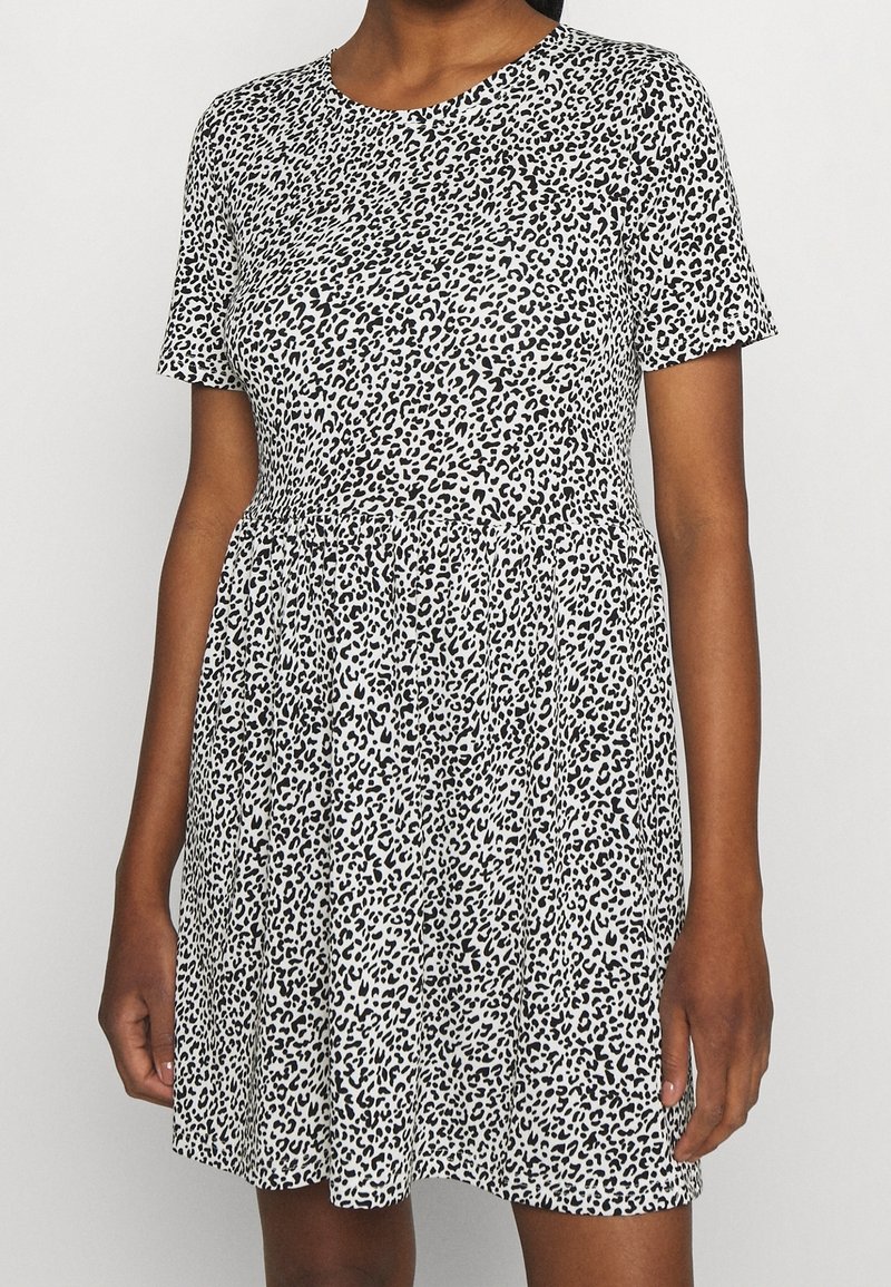 Robe à manches courtes blanche avec un motif léopard noir. Elle possède une taille cintrée et une jupe évasée. Confectionnée dans un tissu léger.