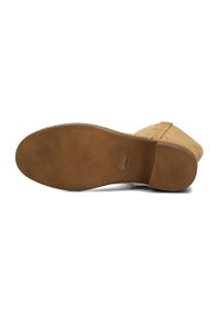 Chaussure en suede beige avec une semelle en caoutchouc texturé ; présente un bout arrondi et un petit talon. La semelle présente un motif pour une meilleure adhérence.