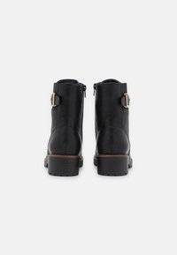 Botine negre din piele cu o textură fină, un fermoar lateral proeminent și o cataramă cu un accent de nuanță aurie. Toc conic pentru un plus de înălțime.