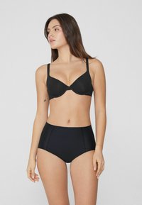 Schwarzer BH mit gepolsterten Cups, dünnen verstellbaren Trägern und nahtlosem Design, kombiniert mit hochgeschnittenen schwarzen Unterhosen, beide aus glattem Material.