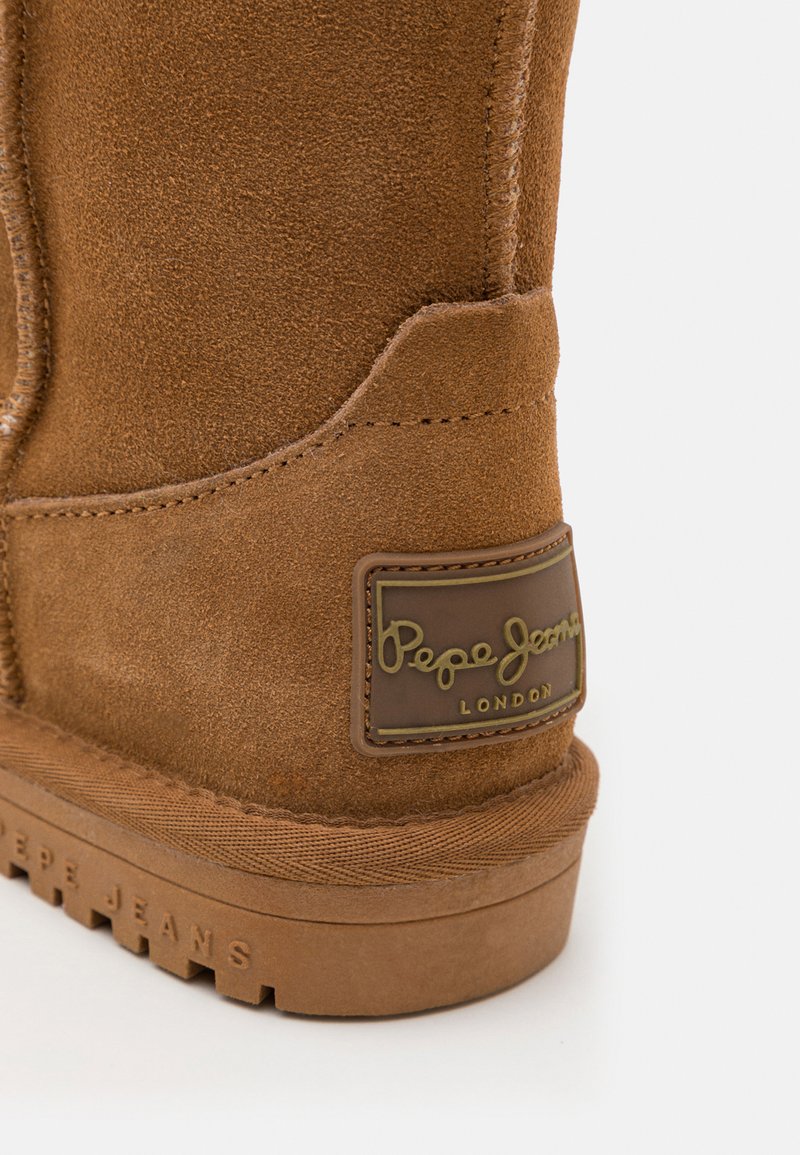 Bottine en daim marron avec une finition texturée, dotée d'une semelle en caoutchouc et d'un patch marqué "Pepe Jeans London" en or.