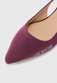 Burgundi színű, hegyes orrú balerinák, rugalmas anyagból, puha bélésű belső résszel. A külső oldalon fehér színnel van nyomtatva a "LOVE MOSCHINO" felirat.