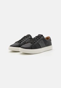 Sorte lær sneakers med en teksturert grå panel, hvit gummisåle og sorte snørebånd. Glatt overflate med minimale sømdetaljer.