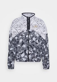 Svart och vit bomberjacka med blommönster, spetsdetaljer på axlarna, full dragkedja och en liten guldig logodetalj.