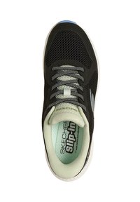 Zapatillas de malla negras con cordones grises, que presentan una plantilla verde menta y una suela blanca. Logo visible en el costado.