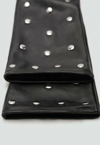 Cartera de cuero negra con tachuelas metálicas en la parte frontal. Textura suave, forma rectangular y diseño plegado. Presenta acentos espaciados uniformemente.