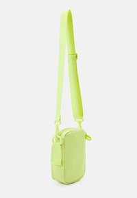 Borsa a tracolla verde neon con forma rettangolare, texture liscia, tracolla regolabile e chiusura con cerniera dotata di una piccola tasca accessoria.