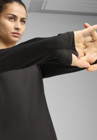 Must asetusega must pikkade varrukatega topp, millel on sobiv disain, käeotste thumbhole'ide funktsioon, sujuv tekstuur ja peened õmbluse detailid.