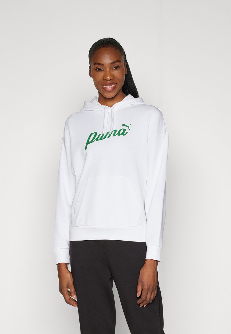 Sudadera blanca con un logo "Puma" verde, cordones, bolsillo tipo canguro y puños acanalados. Usada con pantalones negros, textura de tela lisa.