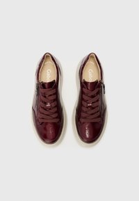 Baskets en cuir bordeaux avec une finition brillante, dotées de lacets marron foncé et d'une fermeture éclair sur le côté. Semelle intérieure rembourrée beige et semelle en caoutchouc gris clair.