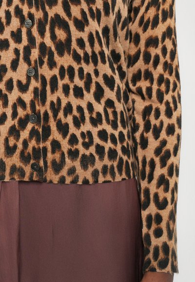 Leopard print cardigan in warm tan with black spots, featuring button closures and ribbed texture, paired with a brown skirt.