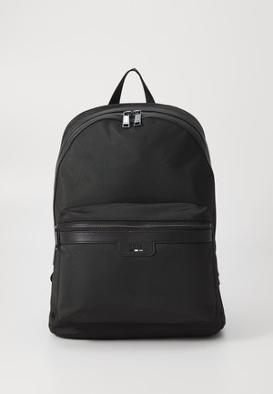 Schwarzer Rucksack mit einer strukturierten Stoffoberfläche, gewölbtem oberen Ende, doppelt silbernen Reißverschlüssen und einer vorderen Reißverschlusstasche mit einem Logoplate.