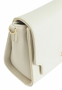 Biała torebka ze strukturalnym kształtem, wykonana z teksturowanej skóry, z detalem złotego metalowego pierścienia po boku i czystym designem bez widocznego hardware'u.