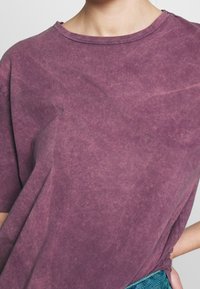 Lila, oversized t-shirt tillverkad av mjuk bomull. Har en rund halsringning och subtil textur med ett urblekt, slitet utseende.