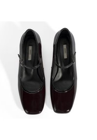 Chaussures Mary Jane en cuir verni bourgogne avec un bout carré, une sangle fine et une doublure intérieure noire, présentant une finition lisse et brillante.