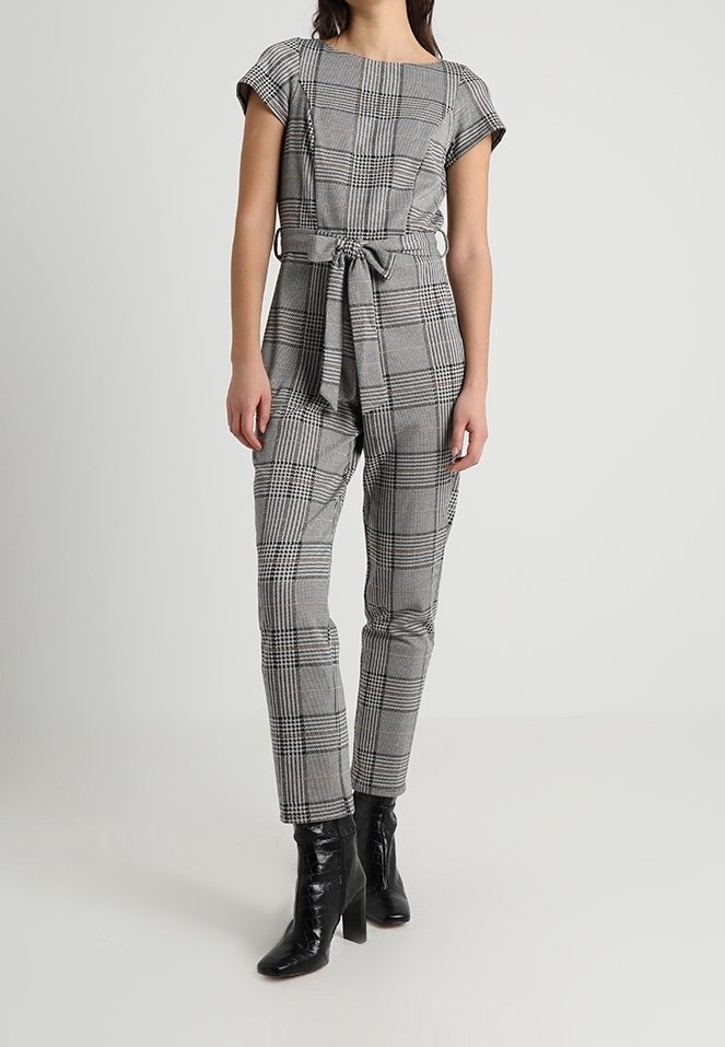 Gray plaid jumpsuit with short sleeves, belted waist, and tapered legs. Worn with shiny black ankle boots. Smooth texture.
