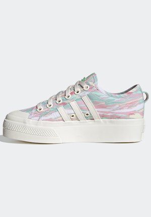 Baskets basses avec un motif tie-dye pastel, semelle en caoutchouc blanc, lacets crème et trois rayures blanches sur le côté.