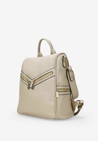 Zaino in finta pelle beige con doppia cerniera dorata, bordi neri, manico superiore, spallacci regolabili e un design strutturato.