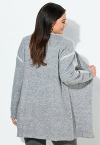 Ljusgrå cardigan med långa ärmar, stickad textur, öppen front, ribbad nederkant och subtila randdetaljer på axlarna.