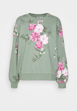 Jasnozielona bluza z kwiatowymi wzorami w różu i bieli, z okrągłym dekoltem, ściągaczami na rękawach i luźnym krojem.