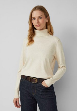 Beige coltrui van zacht materiaal, met lange mouwen, een relaxte pasvorm en een geribbelde kraag, gecombineerd met donker denim jeans en een brown riem.