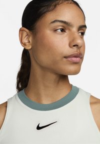 Nike sporttanktop in lichtgroen met een contrasterende blauwe kraag, voorzien van een zwart logo op de borst, gemaakt van een gladde, ademende stof.