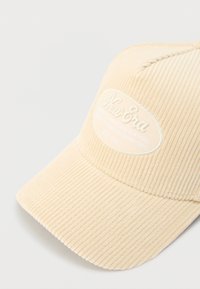 Kreemikas sametkangast nokamüts kaardus viskooriga. Omab tekstuurset pinda ja valget plaastrit, millel on "New Era" bränding.