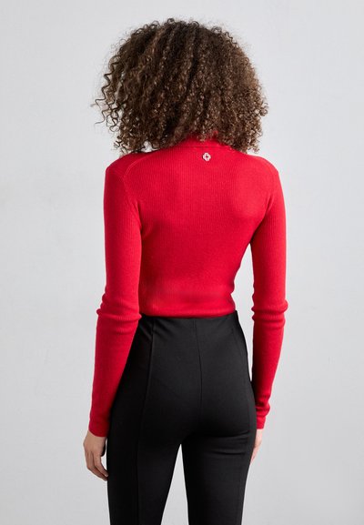 Röd ribbad långärmad topp, figurnära design med rund hals, med en liten logodetalj bak, matchad med svarta högmidjade byxor.