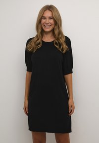 Robe noire en tricot avec des manches courtes bouffantes, un col rond et une longueur au genou. Texture lisse avec une coupe décontractée.