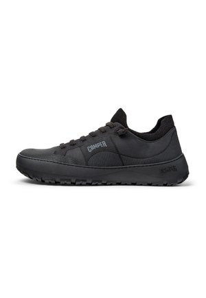 Des chaussures de sport noires avec une tige en tissu texturé, une semelle en caoutchouc et des lacets. Présente un logo de marque bien visible sur le côté.
