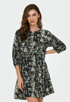 Robe à motif noir et vert avec une coupe décontractée, un col rond et des manches trois-quarts. Tissu doux avec une apparence texturée.