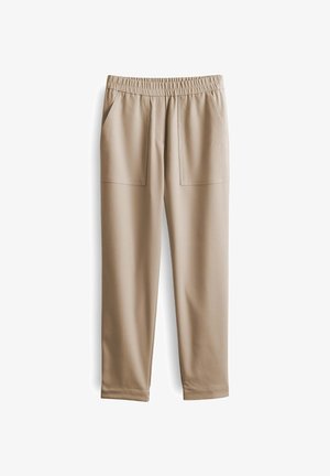 Pantaloni beige con vita elastica, due tasche frontali, design a gamba affusolata e texture liscia, perfetti per un look casual.
