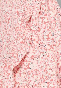 Abito floreale in tessuto rosa chiaro con accenti arricciati. Presenta un motivo di piccoli fiori in varie tonalità di rosa e blu.