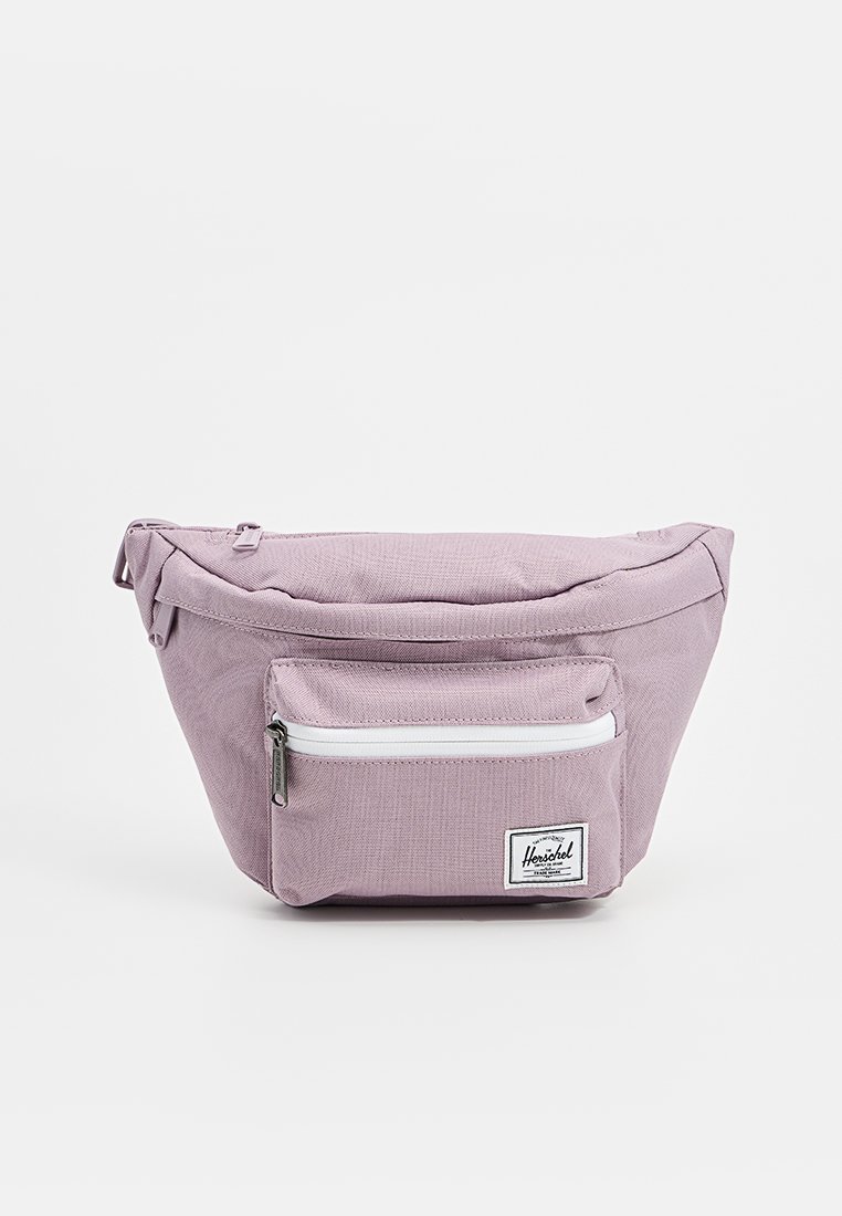 Sac hip en tissu violet avec une surface texturée, doté d'une poche zippée blanche à l'avant et d'une étiquette de logo. Contient un compartiment principal avec une fermeture éclair.