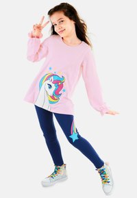 Rosa Langarmshirt mit einem Einhorn-Motiv und bunten Sternen, kombiniert mit dunkelblauen Leggings, die mit Regenbogen- und Stern-Akzenten verziert sind.