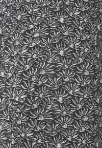 Tessuto nero con un motivo floreale bianco che presenta forme arrotondate e foglie dettagliate. La texture appare leggermente intrecciata.