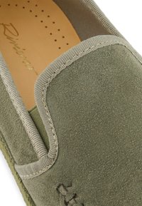 Green suede slip-on shoe with a textured surface, contrasting beige stitching, and a soft, cushioned insole featuring perforations.