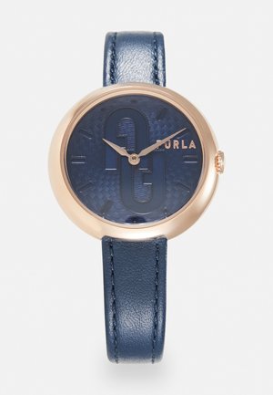 Mornarski kožni sat s okruglim kućištem u ružičastom zlatu, teksturiranom tamnoplavom brojčanikom, istaknutim logotipom i minimalističkim oznakama sati.