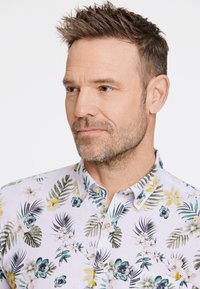 Korte mouwen bloemenoverhemd in lichte stof met groene bladeren en gele bloemen, voorzien van een button-down kraag en tan kleurige knopen.