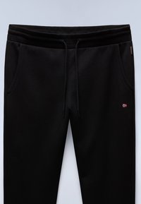 Zwarte sweatpants met een geribde tailleband en een trekkoord. Bevat twee zijzakken en een klein accentlogo aan de linkerkant.