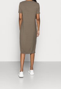 Khaki midi sukienka z krótkimi rękawami, dopasowany fason, gładka tekstura i okrągły dekolt, w połączeniu z białymi sneakersami.